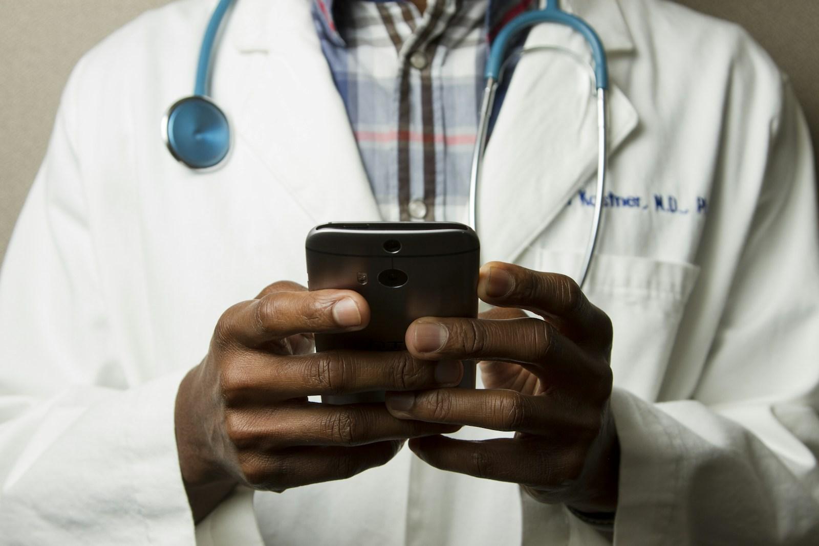 Healthcare professional wearing a stethoscope and holding a mobile device